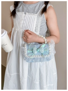 Detail of light blue lace kids handbag featuring a large holographic bow and pearl handle