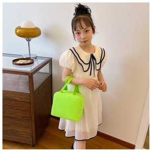 Neon green canvas lunch bag shown held by a girl in a bright minimalist interior setting