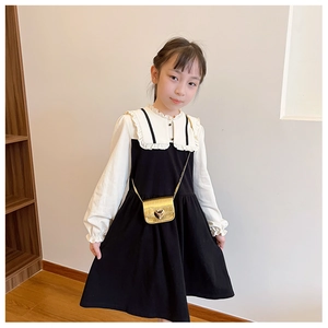 Detail einer goldenen Herz-Mini-Umhängetasche mit einem schwarz-weißen Kleid