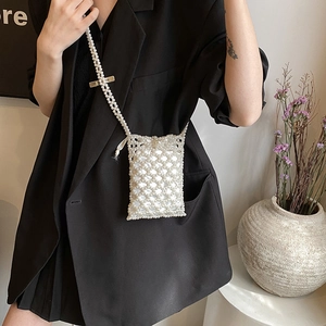 Elegant white pearl woven crossbody bag with drawstring satin liner on a black blazer