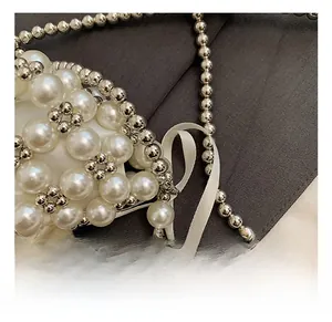 Detail of woven pearl beads with silver accents and a white satin ribbon on a girl's handbag