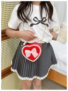 Detail of red heart-shaped girls purse with pearl handle and pink bow on lace texture