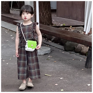 Détail d'un ensemble fille avec haut à volants marron à carreaux et pantalon large