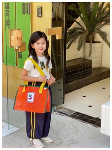 Détail du sac bandoulière en filet pour enfants avec maille orange et poignée jaune vive