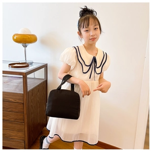 Close-up of a minimalist black canvas tote bag for kids with durable handles and metal zipper