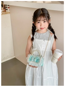 Detail of mint green lace mini bag with pearl trim and bow worn by a child
