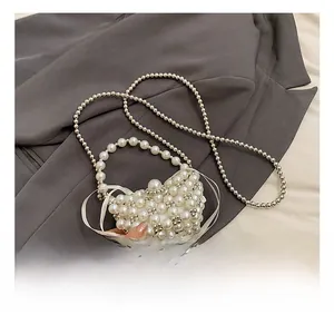 Detail showing the white pearl beaded mini bag with a satin bow and silver chain strap