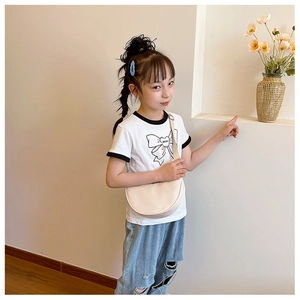 Detail shot of a beige semi-circle crossbody bag styled with casual children fashion