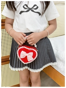 Detail of red heart-shaped girls purse with pink bow, pearl handle and lace trim