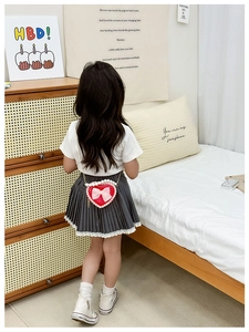 Rear view of a girl wearing a red heart-shaped pearl bag with pink bow and lace skirt