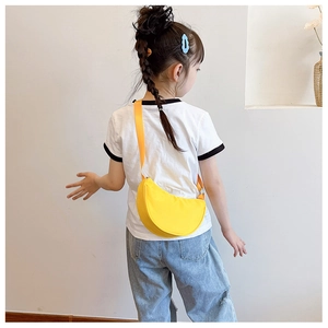 Detail of bright yellow semi-circle crossbody bag on a child model in a home setting