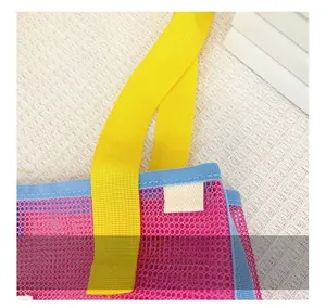 Détail du passepoil bleu renforcé et de l'anse tissée jaune sur le sac de plage en maille