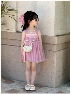 Girl in light pink layered tulle dress with pearl crossbody bag and matching accessories