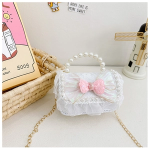 Detail of pink sequin bow and lace ruffles on white girls' crossbody bag with pearl handle
