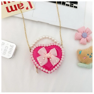Detail of pink heart-shaped girl's bag with lace trim, pearl handle and mesh bow ornament