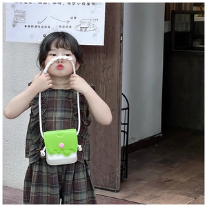 Fillette portant un mini sac bandoulière vert et crème avec bouton rose stylé