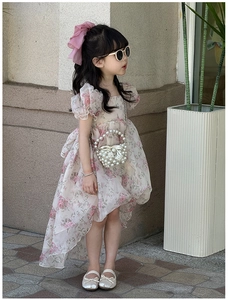 Detail of a floral girl dress with puff sleeves, pearl handbag, and cute accessories