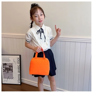 Close-up of bright orange canvas lunch bag with zipper and handles for students