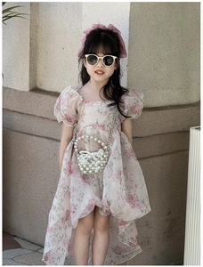 Detail of sweet floral girl's dress with puffy sleeves and mini pearl chain handbag