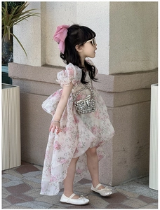 Detailed side view of floral princess dress with tiered ruffled hem and pearl handbag