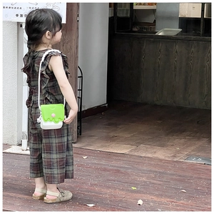 Détail d'un enfant portant un sac à bandoulière en silicone vert et blanc style crème glacée