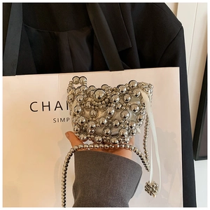 Detailed close-up of a silver beaded mini bag with a pearl strap and white inner lining