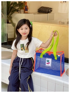 Détail d'un sac de plage enfant en mesh aux couleurs contrastées et écusson fleuri