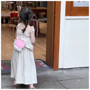 Vue de dos d'un enfant portant un sac à bandoulière contrasté rose et blanc stylé