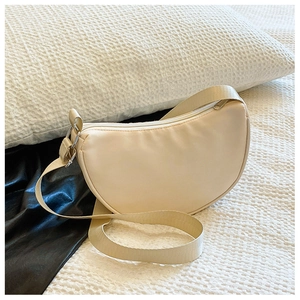 Detail of a beige half-moon nylon crossbody bag with adjustable strap and metal zipper
