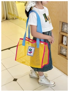 Détail du sac bandoulière en maille colorée porté par un enfant dans une boutique chic