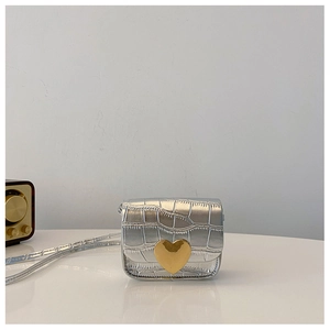 Makroaufnahme der silbernen Krokostruktur-Tasche mit goldenem Herz-Metallverschluss