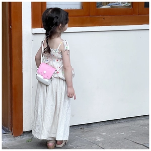Détail d'un mini sac à bandoulière rose et blanc sur une robe d'été pour enfant