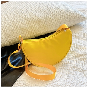 Detail of a bright yellow semi-circular crossbody bag with silver hardware on white fabric