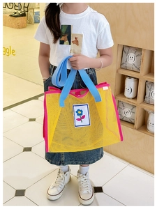 Détail du sac de plage enfant en maille jaune avec bordure rose et fleur brodée