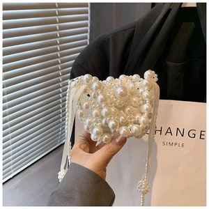 Close-up of heart-shaped pearl handbag with white satin ribbon and pearl chain strap