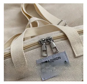 Detail of dual metal zippers and college style patch on a canvas diaper bag