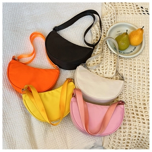 Detailed row of kids semi-circular crossbody bags in five bright colors on white fabric