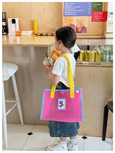 Vue détaillée du sac en maille rose avec anses jaunes et écusson de tournesol brodé