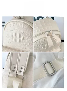 Detail view of cream faux crocodile texture, dual zippers and metal hardware on backpack