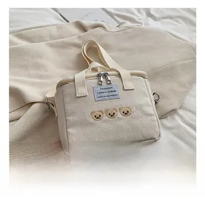 Detail of cute bear embroidery and dual zippers on cream canvas diaper bag