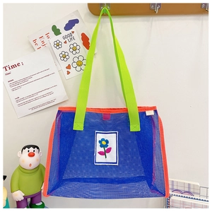 Détail du sac cabas en filet bleu avec bordure orange et poignées en sangle vert vif