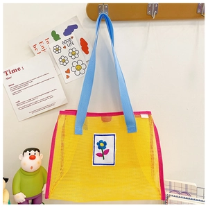 Détail du sac en maille pour enfants avec écusson floral bleu et bords roses
