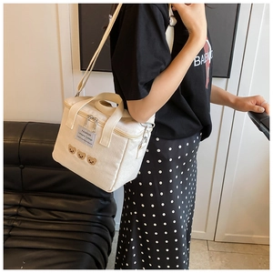 Detail of canvas diaper bag featuring cute bear embroidery and dual metal zippers