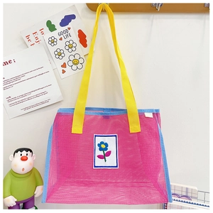 Détail du sac bandoulière en maille rose pour enfant avec bretelles jaunes et broderie