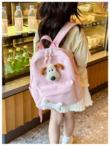 Pink kids backpack featuring a plush cartoon dog head and bone zipper in a shop setting