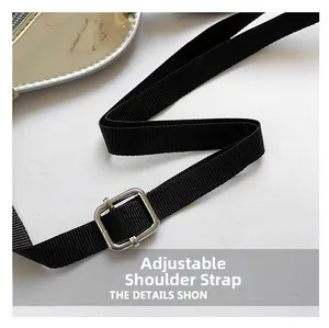 Macro detail of adjustable black nylon shoulder strap with silver metal buckle on bag