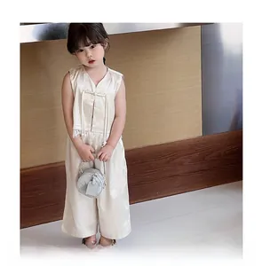 Détail d'un enfant portant un gilet beige de style oriental et un pantalon large assorti