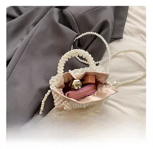 Detailed view of the woven pearl handbag's pink satin interior and its storage capacity