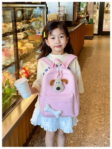 Detail of pink kids backpack featuring a plush puppy face and bone shaped charm