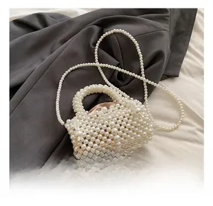 Detail of handmade pearl woven bag featuring white satin bows and polished bead texture